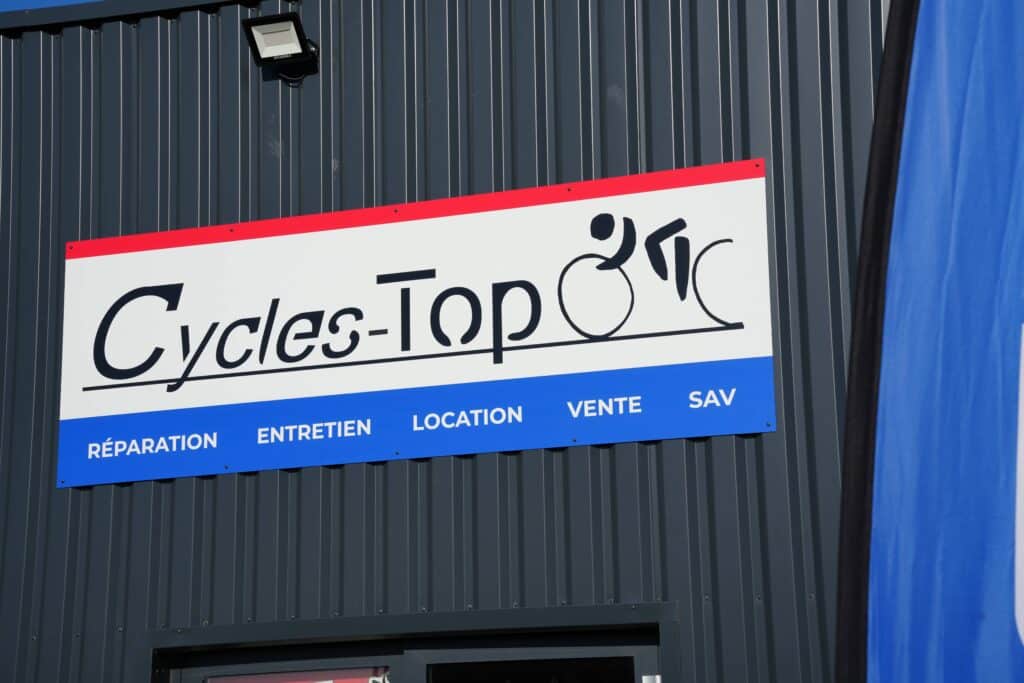 enseigne du magasin Cycles-Top fixée en façade avec typographie visible et identité graphique reconnaissable